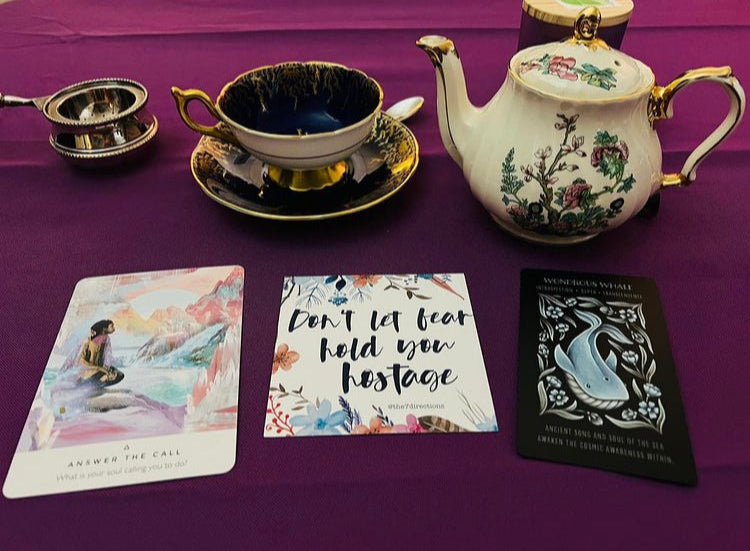 Tea set with cards on a purple surface.
