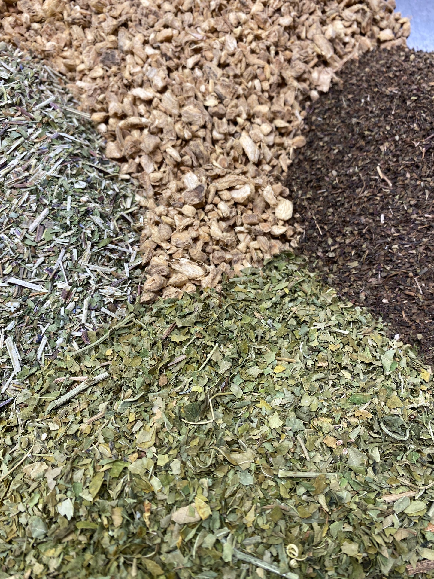 Ginger, Tulsi, Skullcap, Passionflower herbs poured next to eachother in a large mass.