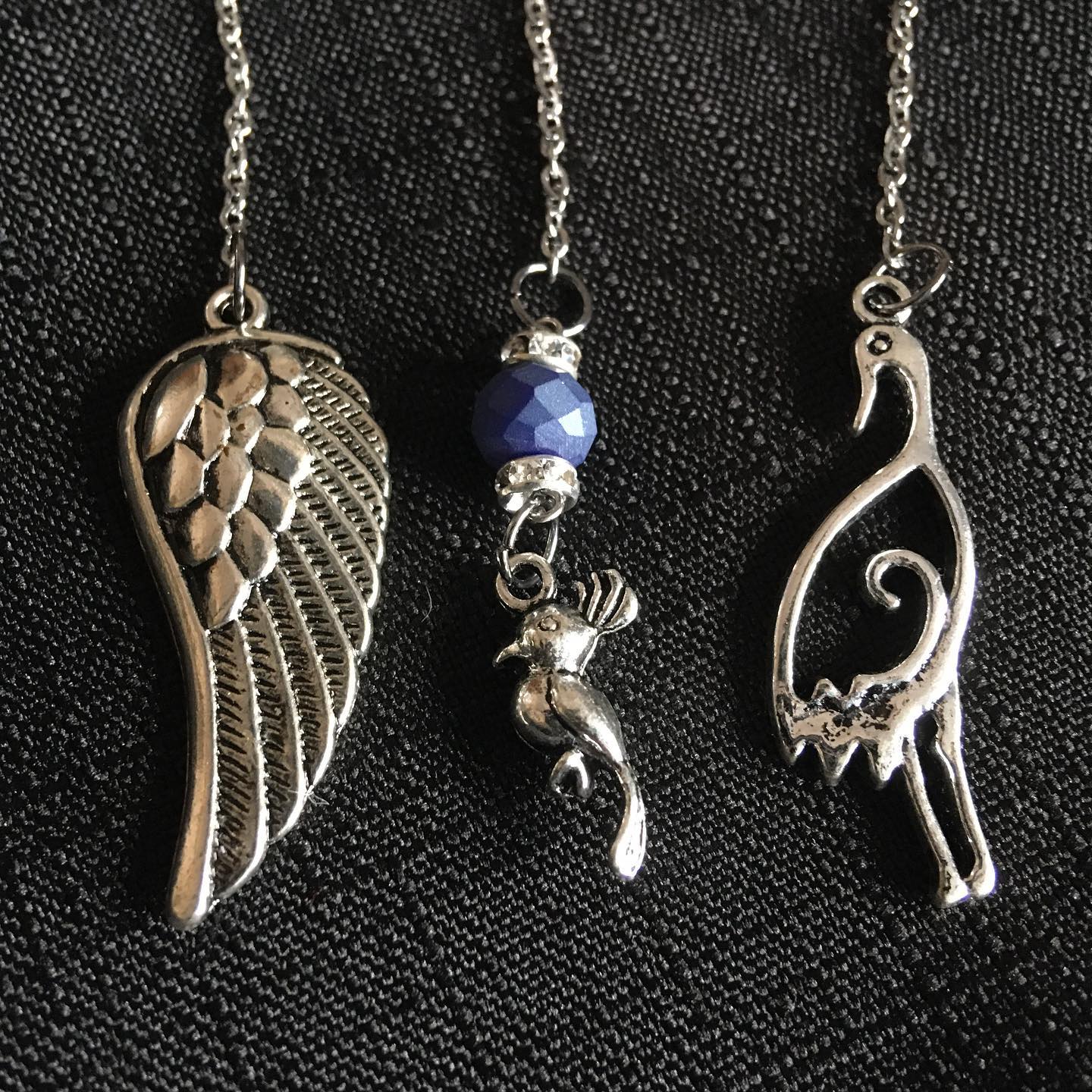 Three silver pendants on a dark textured background