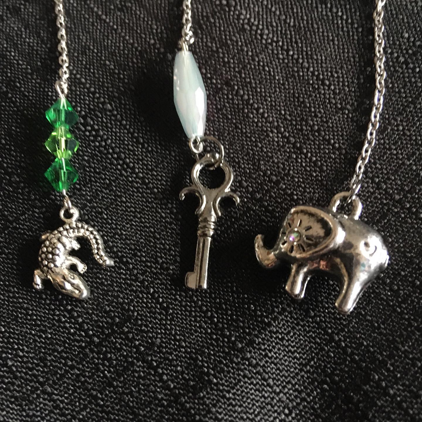 Three silver charms on a chain against a black background
