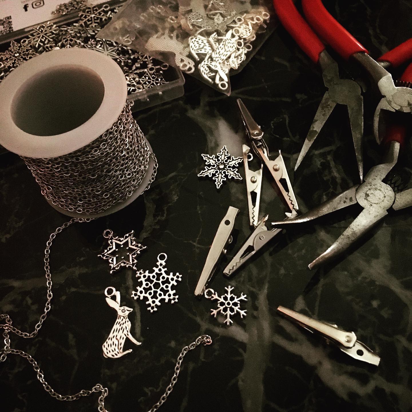 Jewelry-making tools and chain on a dark surface