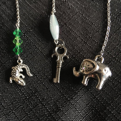 Three silver charms on a chain against a black background